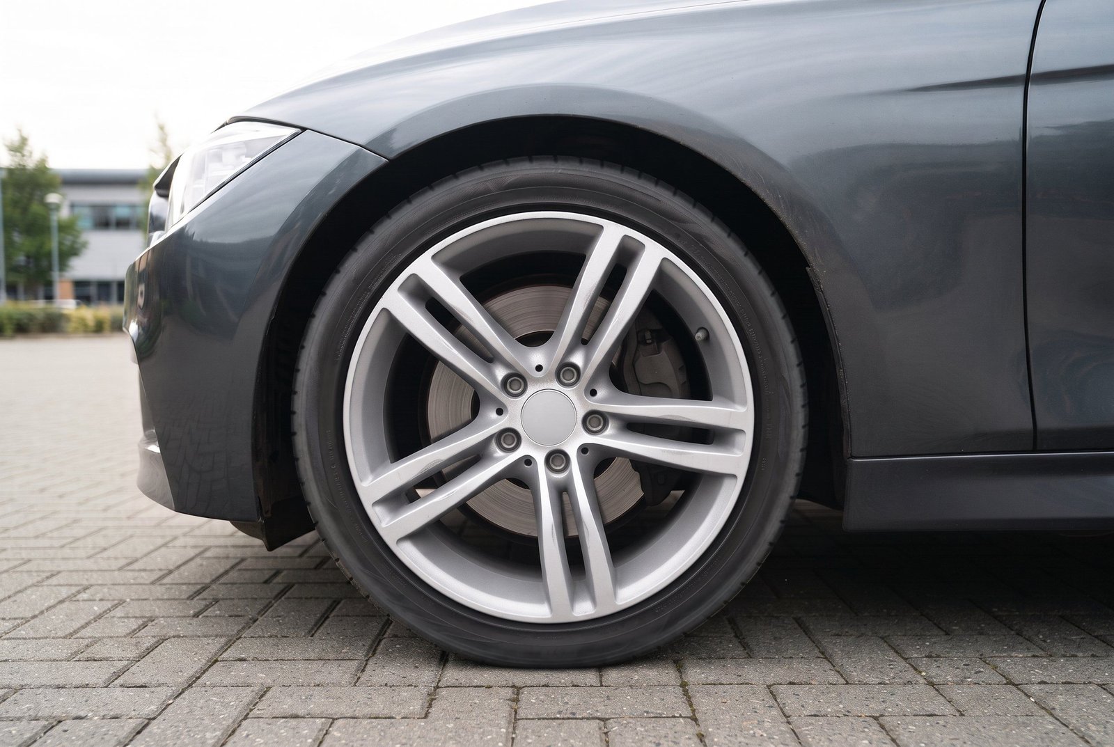 Jante argent nettoyée et pneu noir sur une voiture grise